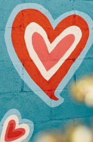 Muro di mattoni azzurro con graffiti a forma di cuore